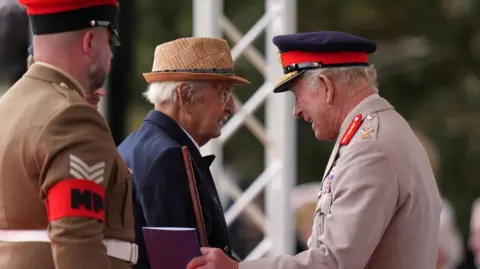 Reuters Britain's King Charles talks to Yavar Abbas as they attend a Service of Remembrance at the National Memorial Arboretum to commemorate the 80th Anniversary of VJ Day 