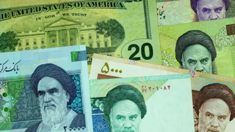 Iranian Ryal notes with pictures of the Ayatollah on, over the top of a US dollar