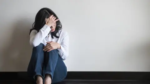 Getty Images A woman sitting alone looking scared