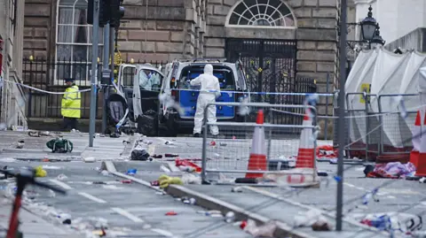 PA Media Forensic officers at the scene in Water Street near the Liver Building in Liverpool after a 53-year-old white British man was arrested when a car ploughed into a crowd of people during Liverpool FC's Premier League victory parade. 