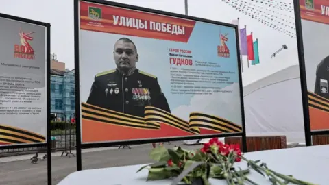 Flowers placed in front of a board with a photograph of Major General Mikhail Gudkov, the deputy head of the Russian Navy