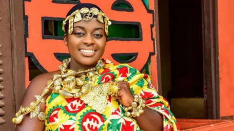 King Larbi Photography Linda Gyamfi wearing Kente cloth, historically worn by royalty. She is also wearing a crown made up of Adinkra symbols and gold body jewellery