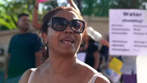 A woman wearing sunglasses is seen at a protest about water issues