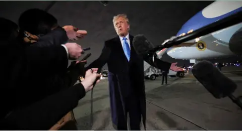 Reuters President Donald Trump is interviewed at night by reporters on the runway beside Air Force One