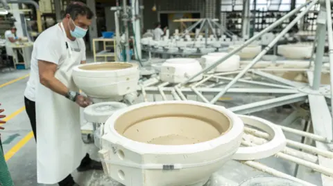 Vista Alegre A worker stands on a production line of large porcelain bowls.