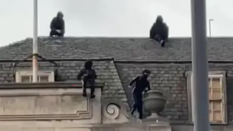 Danni Macrae Four children wearing face coverings are on the roof of the old Debenhams building