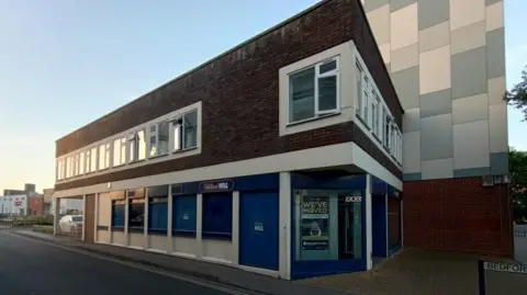 Merkur Slots A building on a corner. There is signage for a William Hill shop.