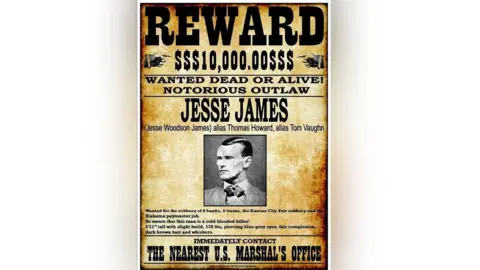 Getty Images Faded at the edges, a black and white "wanted" poster from the 1870s. It shows a headshot of James in his 30s, wearing a smart suit with collar and tie. He has swept-back dark hair. It warns the public that he's dangerous, and offers a reward of $10,000 for his capture.