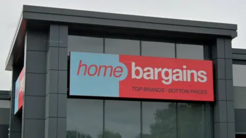 Google A red and blue sign on a grey building. The sign says home bargains, top brands bottom prices