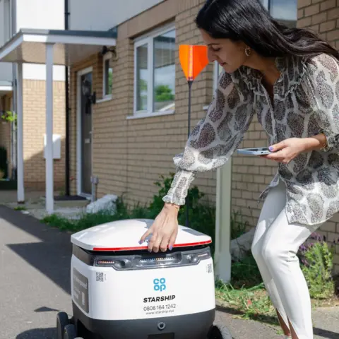 Cambs County Council Woman collecting her goods from a delivery robot