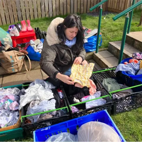 Nicky bent down looking at clothing at the shop