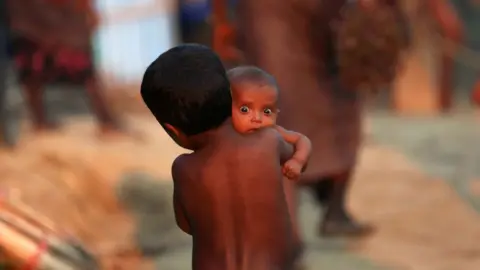 A Rohingya Muslim child carries an infant at a refugee camp in Palang Khali near Cox's Bazar, Bangladesh.