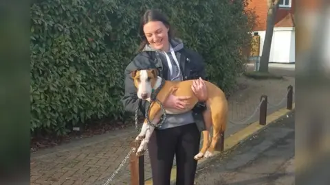 Alice Johnstone-Burt Alice Johnstone-Burt holding a dog in the street and smiling