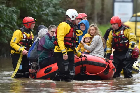 PA Media Residents of Nantgarw in a rescue boat as emergency services take people to safety, after flooding in the village in Wales