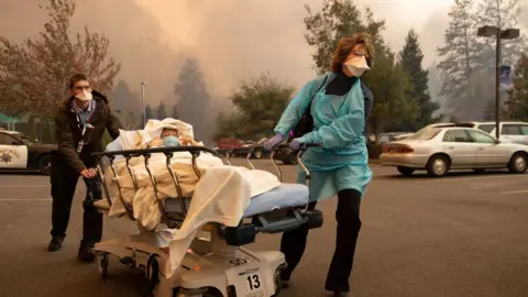 AFP/Getty Patients are quickly evacuated from the Feather River Hospital as it burns down during the Camp fire in Paradise