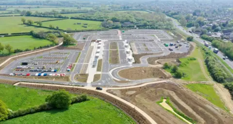 Oxfordshire County Council Eynsham park and ride, which is just a large tarmacked area, with parking spaces marked out, but completely empty. On it's right hand side is the A40 road, which it is not connected to.