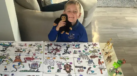 A little boy with 99 animals drawn in front of him for David Attenborough