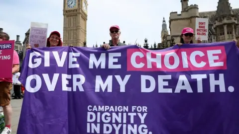 Campaigners in favour of assisted dying bill with banner outside Parliament