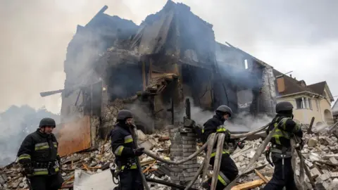 Emergency workers work at the site where private houses were destroyed in a Russian rocket strike, amid Russia's attack on Ukraine, in Markhalivka