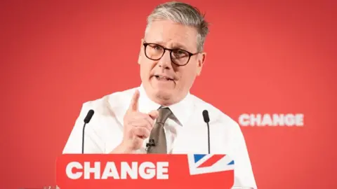 Starmer points as he speaks at a lectern branded "change"