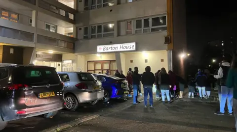 People standing outside Barton House in the car park on the night of the evacuation