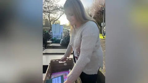 Deputy head Caroline Houghton moving pupils' workbooks in a crate