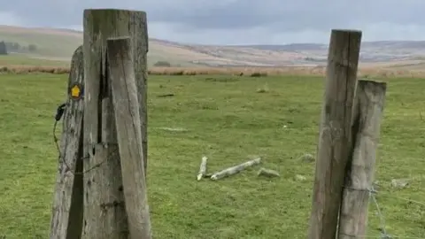 BBC/Spencer Stokes Two wooden posts forming a gateway looking onto moorland and rolling hills.