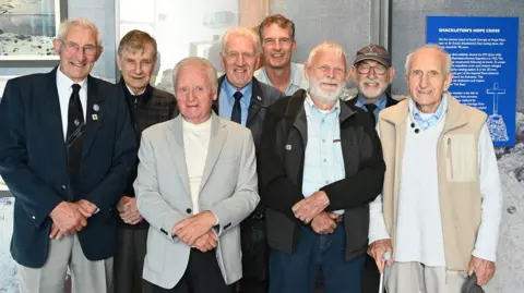 Art Lewry/Culture Communications Collective Dan Snow, back, with a group of former whalers all smiling at the camera.