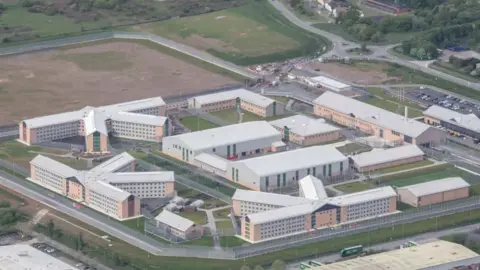 Getty Images An aerial shot of HMP Berwyn showing a square site with various buildings running alongside the edges and a larger building in the middle. Square patches of grass can be seen between the buildings.