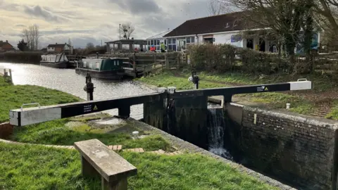 Canal & Rivers Trust A canal lock with two barges moored in the background
