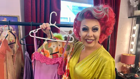 Supplied A woman holds up a pink dress.