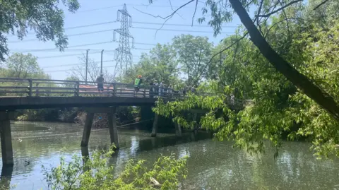 A long shot of the bridge over the river with competitors lined across it.