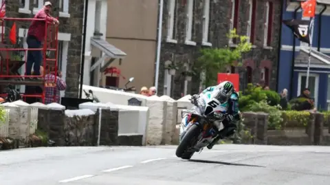 Os visitantes estão assistindo dos jardins da frente da casa ao longo do percurso enquanto corriam com o IOM TT Michael Dunlop Carc Michael.