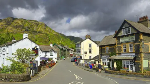 Getty Images Looking down the centre of Coniston Village high street, with mountains in the distance, to the left.
