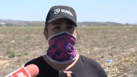 Luz Toscano is covered with mouth and speaks the black baseball hat