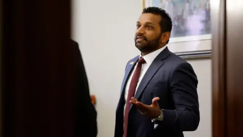 Getty Images Man holds his left hand up while speaking to someone