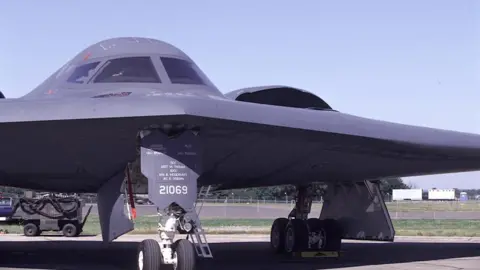 BBC A B2 Stealth Bomber 393 BS US Airforce - a dark grey airplane with flag wings and a rounded top - sits on the tarmac at IAT Air tattoo RAF Fairford