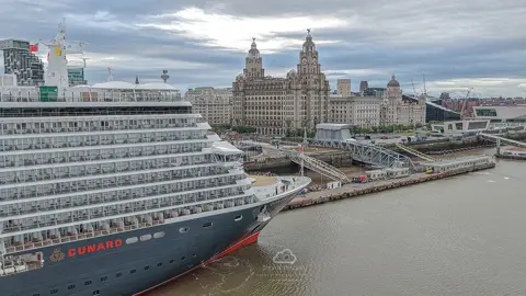 Stratus Imagery View of the Queen Anne Cunard cruise ship docked at Liverpool's waterfront. The city's famous Three Graces are in the background.
