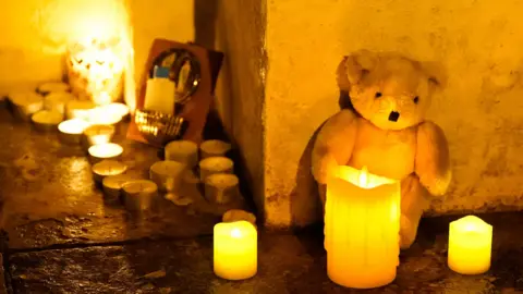 PA Media Candles and a teddy bear 