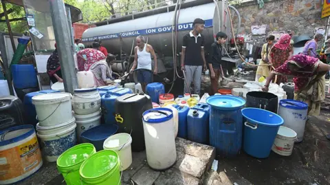Getty Images Residents of a slum cluster collect water from a municipal tanker of the Delhi Jal Board on a hot summer day as the water crisis continues at Sanjay Camp Chanakya Puri on April 21, 2026 in New Delhi, India.