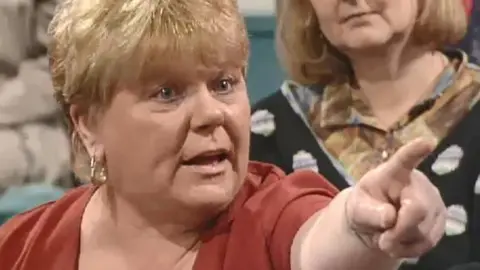 Great Mags in Kilroy. An image caught from the show. Haney's hand is a close -up outside, indicates the accusation. A big gold earrings with blonde hair.