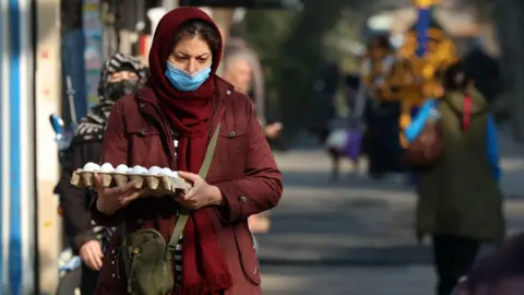 EPA/Shutterstock An Iranian woman holding an egg carton walks at a street market in Tehran, Iran, 07 January 2026.