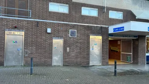 three metal toilet doors in a brick wall