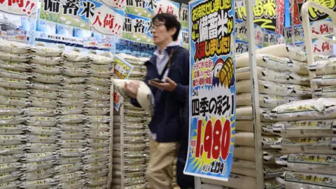 A customer walks past sacks of rice in a supermarket.