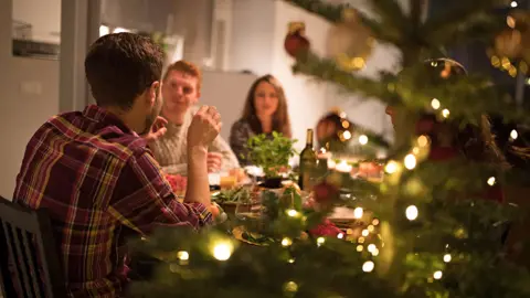 Getty Images A festive meal with Christmas tree and people around a table