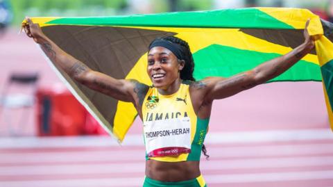 Elaine Thompson-Herah celebrates with a Jamaica flag