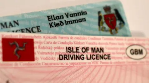 A close-up of a full pink-coloured and blue provisional plastic credit-card sized driving licences. 