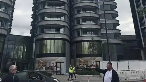 Police tape and two officers can be seen at the foot of a tower block