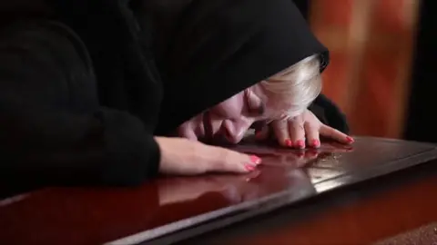 A woman cries over the coffin of a dead soldier