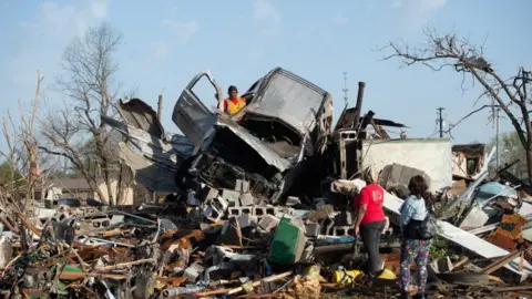 Reuters A man tries to salvage items from a car